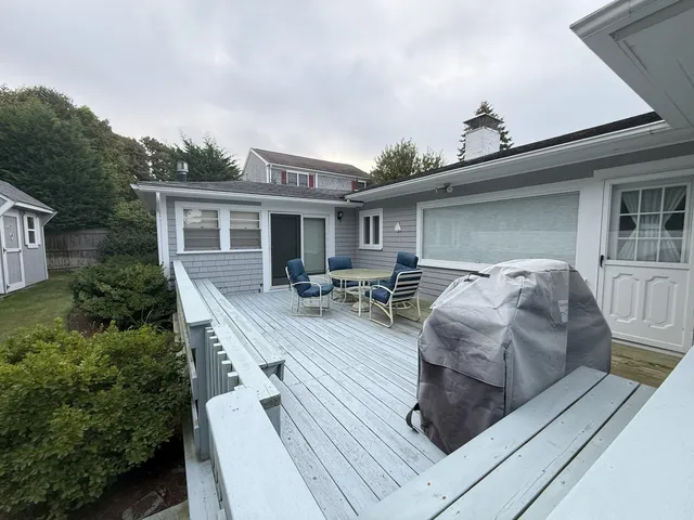 a view of a deck with table and chairs potted plants with wooden floor and fence