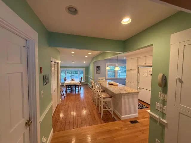 a kitchen with stainless steel appliances granite countertop furniture wooden floor and a view of living room