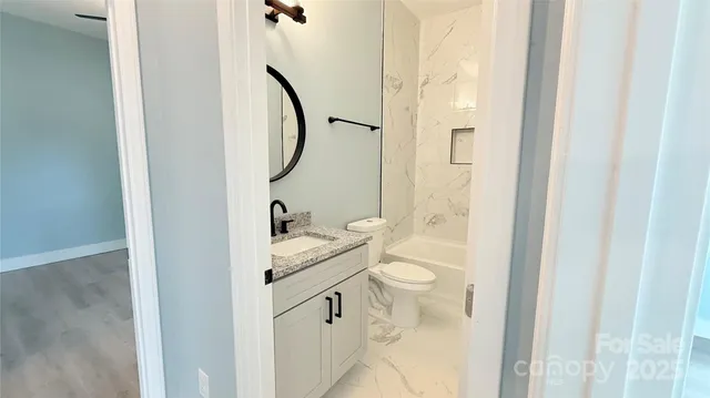 a bathroom with a granite countertop sink toilet and a mirror