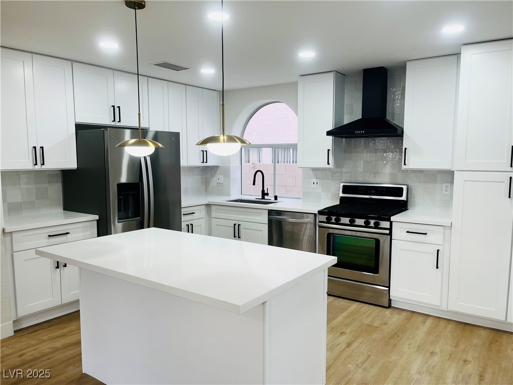 7837 Millhopper Avenue Las Vegas, NV 89128 - Photo 11 of 28 Kitchen featuring white cabinetry, stainless steel appliances, wall chimney range hood, and decorative backsplash