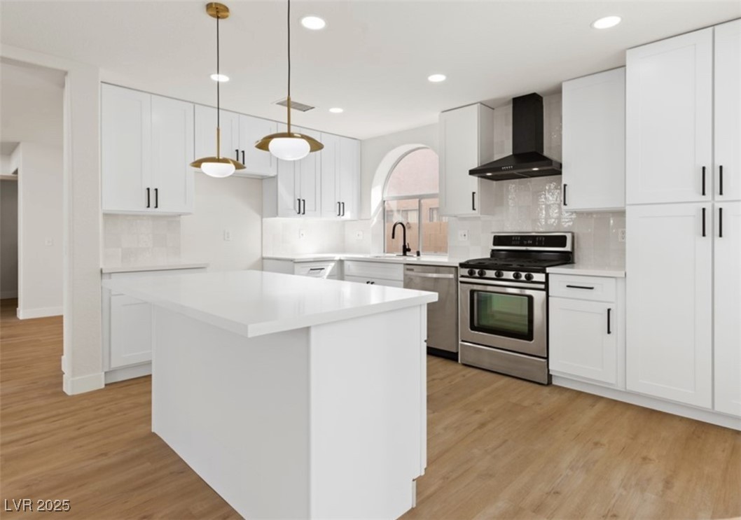 7837 Millhopper Avenue Las Vegas, NV 89128 - Photo 12 of 28 Kitchen featuring white cabinetry, stainless steel appliances, wall chimney range hood, and decorative backsplash