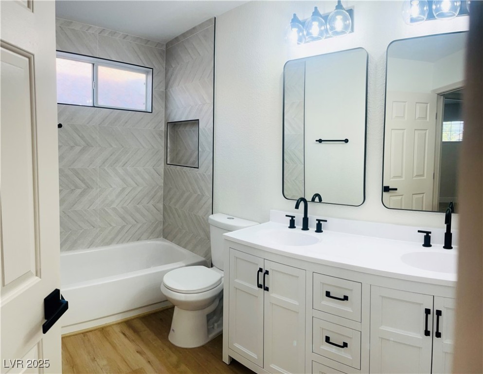 7837 Millhopper Avenue Las Vegas, NV 89128 - Photo 20 of 28 Full bathroom featuring double vanity, light wood-style flooring, and washtub / shower combination
