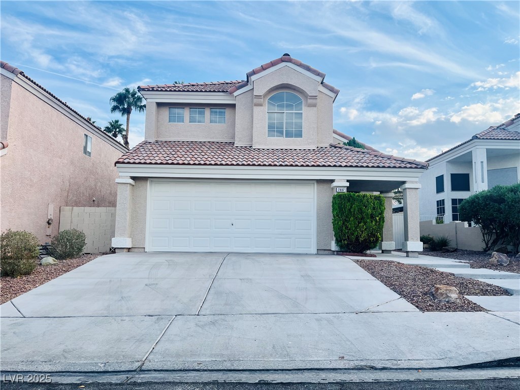 7837 Millhopper Avenue Las Vegas, NV 89128 - Photo 2 of 28 Mediterranean / spanish home featuring concrete driveway, stucco siding, an attached garage, and a tiled roof