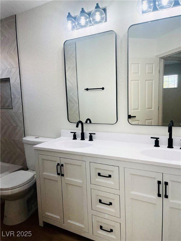 7837 Millhopper Avenue Las Vegas, NV 89128 - Photo 21 of 28 Bathroom featuring double vanity, dark wood-style floors, and shower / tub combination