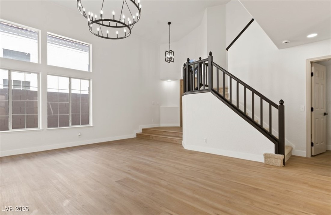 7837 Millhopper Avenue Las Vegas, NV 89128 - Photo 3 of 28 Unfurnished living room with healthy amount of natural light, light wood finished floors, washer / dryer, and stairs