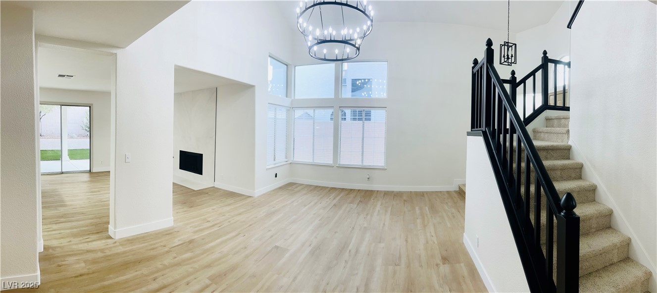 7837 Millhopper Avenue Las Vegas, NV 89128 - Photo 4 of 28 Unfurnished living room with healthy amount of natural light, light wood finished floors, washer / dryer, and stairs