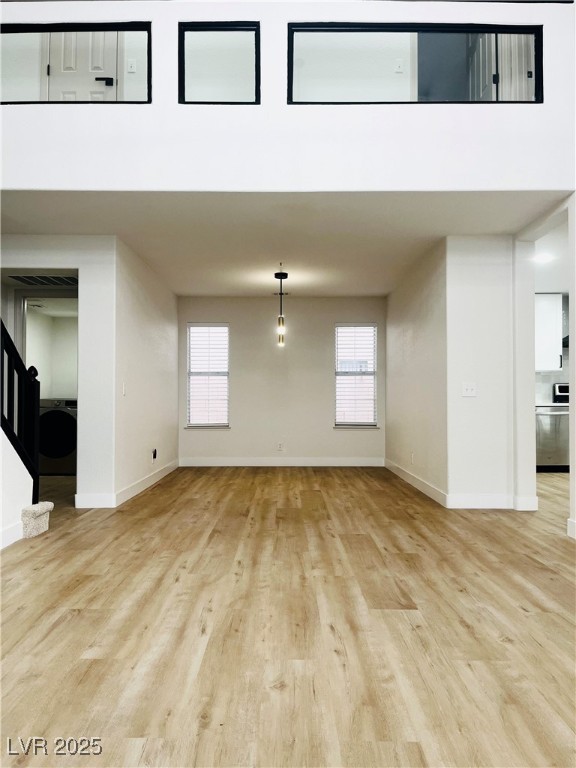 7837 Millhopper Avenue Las Vegas, NV 89128 - Photo 5 of 28 Unfurnished living room with healthy amount of natural light, light wood finished floors, washer / dryer, and stairs