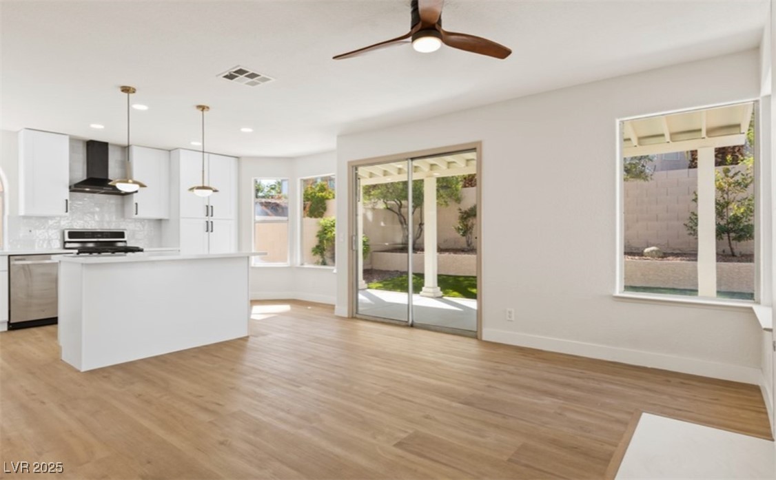 7837 Millhopper Avenue Las Vegas, NV 89128 - Photo 7 of 28 Kitchen featuring light wood-style floors, decorative light fixtures, a premium fireplace, and a center island