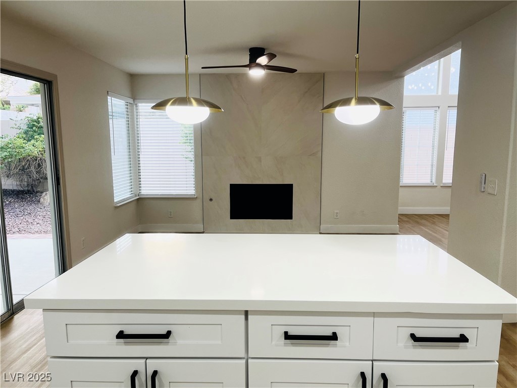 7837 Millhopper Avenue Las Vegas, NV 89128 - Photo 8 of 28 Kitchen featuring light wood-style floors, decorative light fixtures, a premium fireplace, and a center island