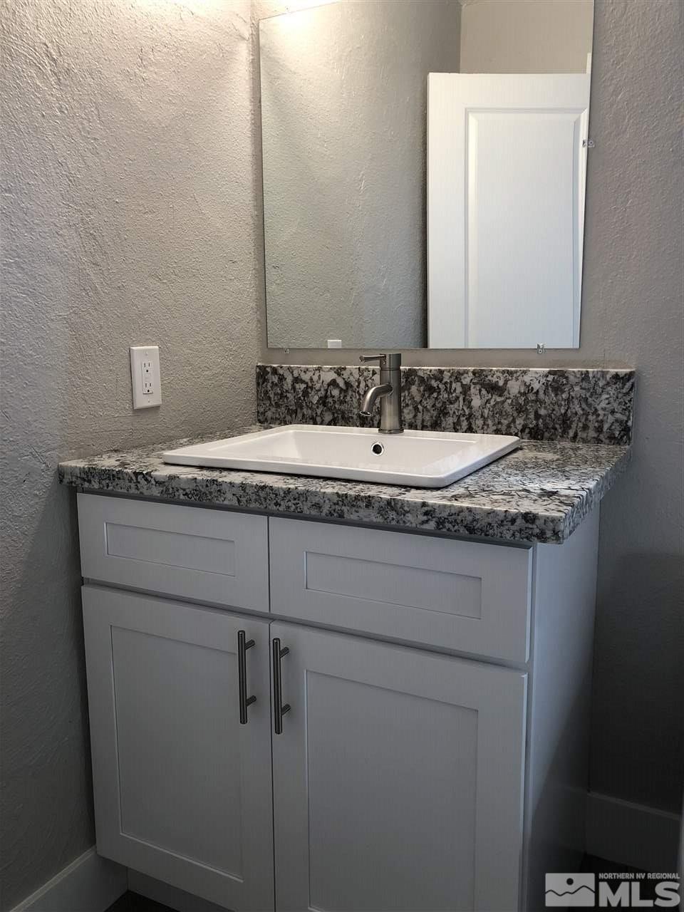10028 Humite Lane Reno, NV 89506 - Photo 7 of 9 a bathroom with a granite countertop sink and a mirror