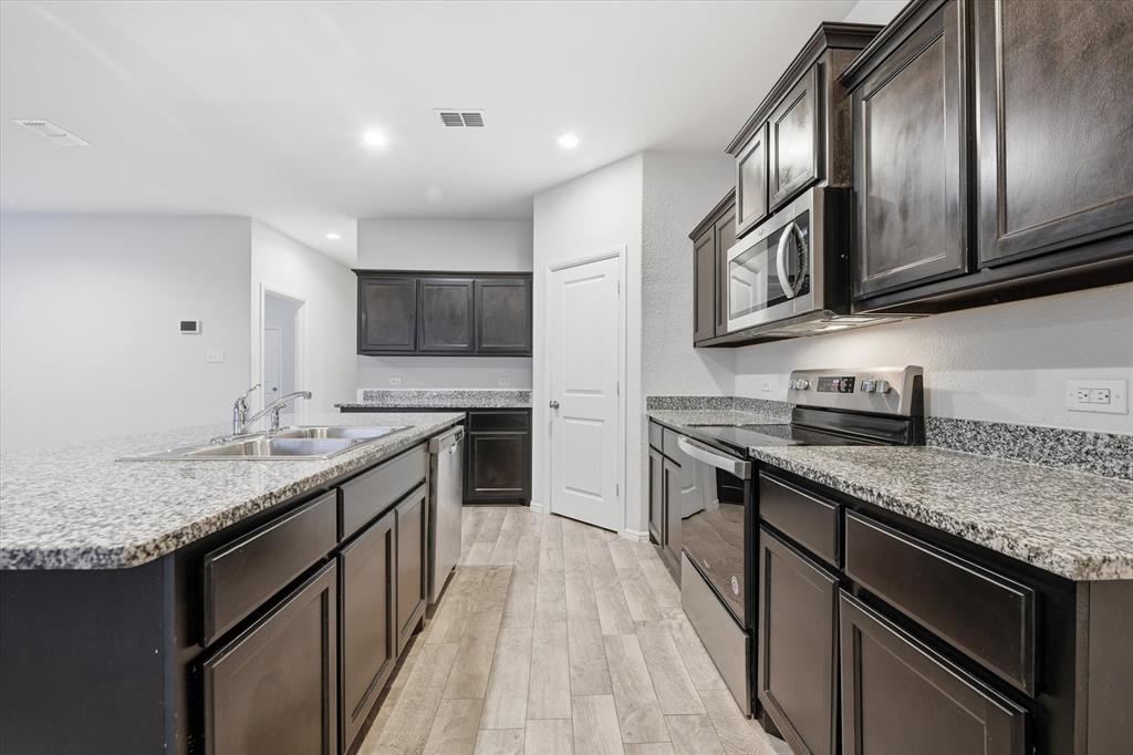 9308 Desertrock Road Fort Worth, TX 76131 - Photo 6 of 23 a kitchen with stainless steel appliances granite countertop a sink stove microwave and cabinets