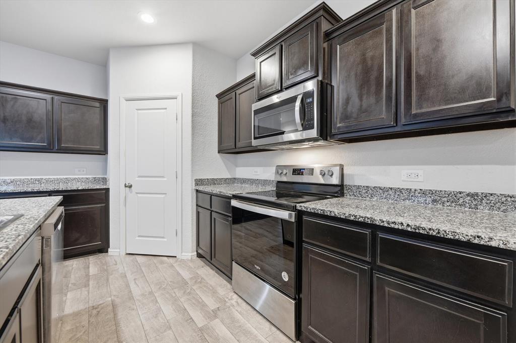 9308 Desertrock Road Fort Worth, TX 76131 - Photo 7 of 23 a kitchen with stainless steel appliances granite countertop a stove microwave and cabinets