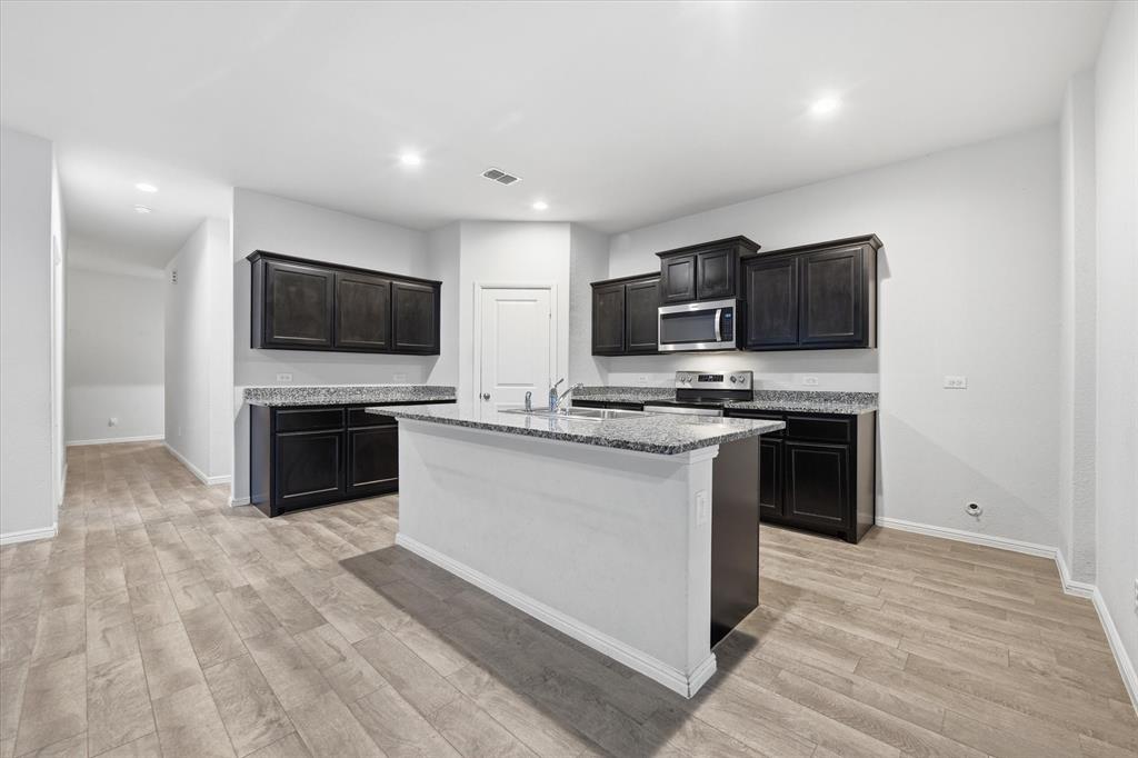 9308 Desertrock Road Fort Worth, TX 76131 - Photo 8 of 23 a kitchen with microwave a stove and cabinets