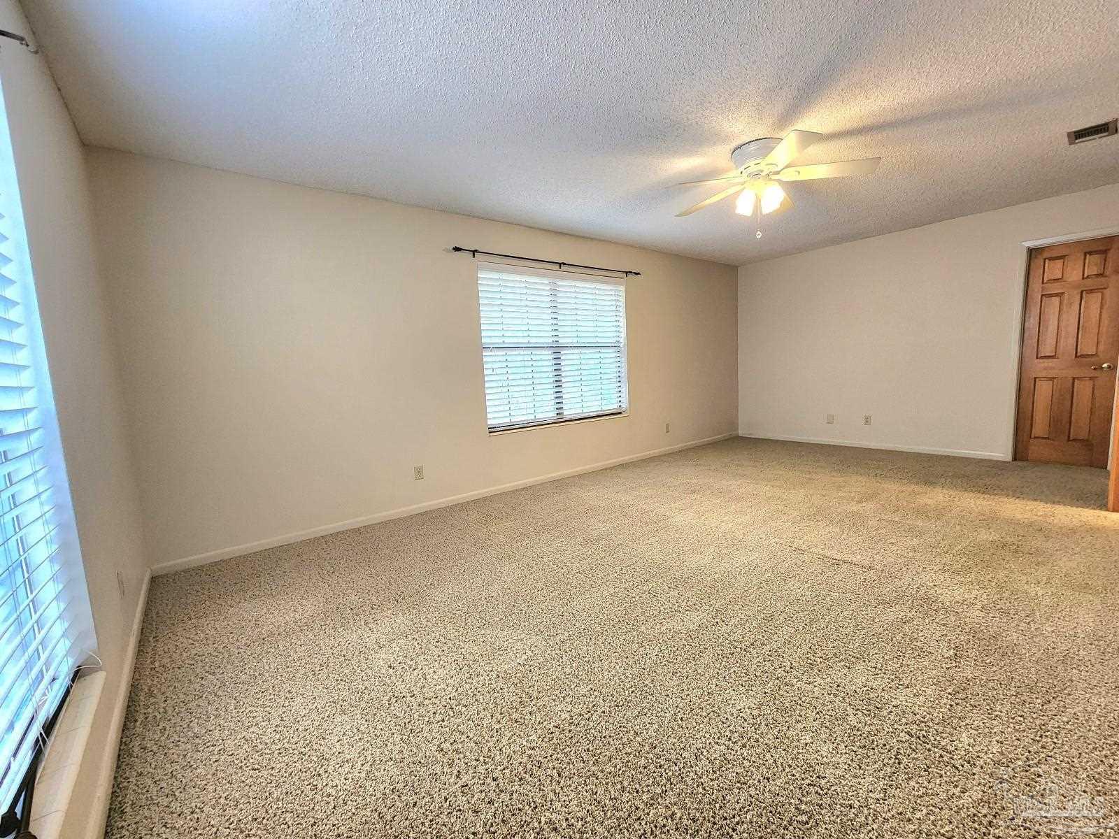 9001 Woodrun Road Pensacola, FL 32514 - Photo 13 of 24 an empty room with windows and chandelier fan