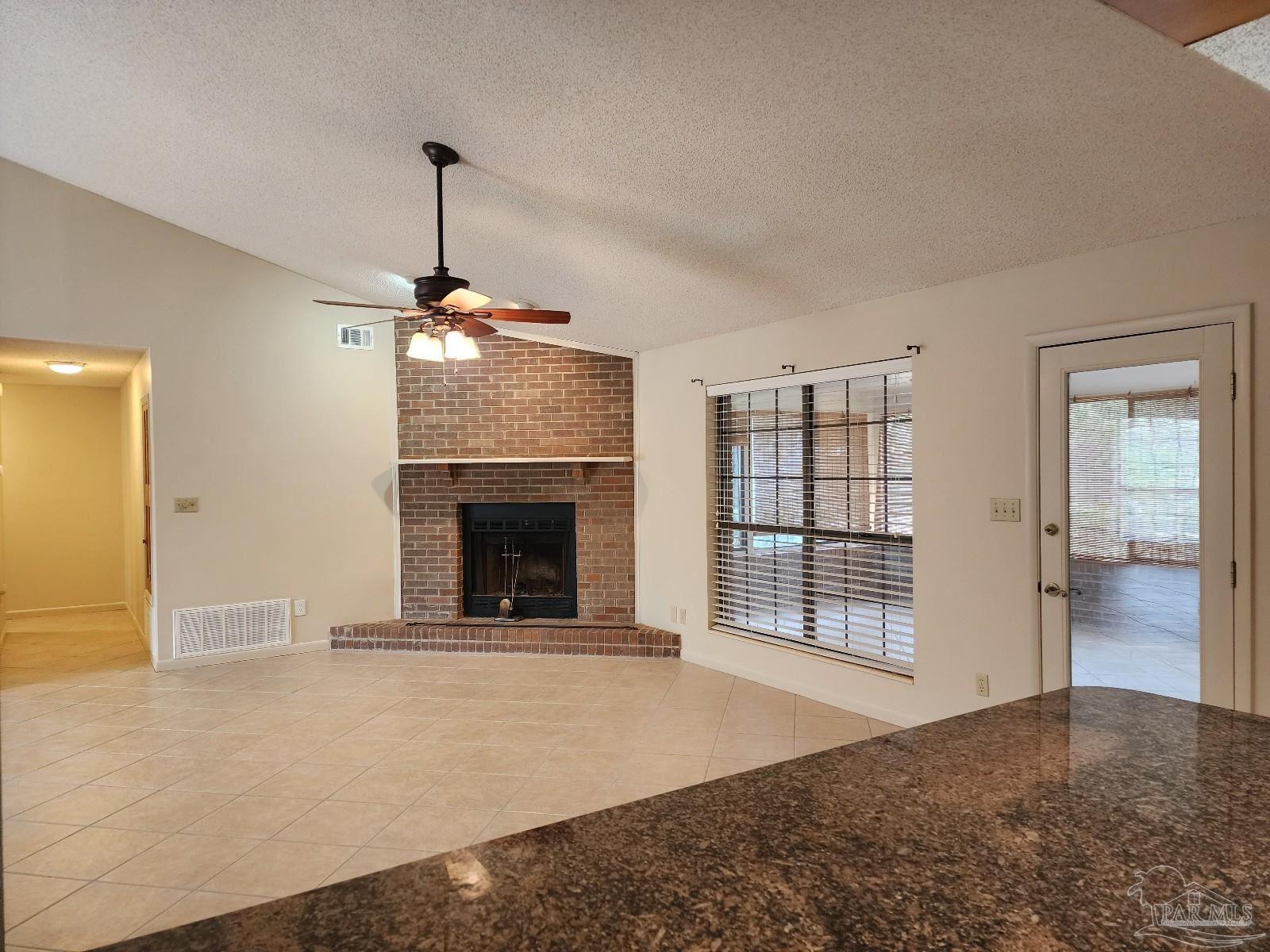 9001 Woodrun Road Pensacola, FL 32514 - Photo 8 of 24 a view of an empty room with a fireplace and a window