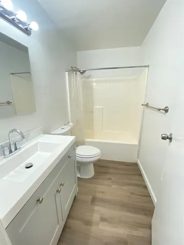 a bathroom with a granite countertop sink a toilet a large mirror and shower