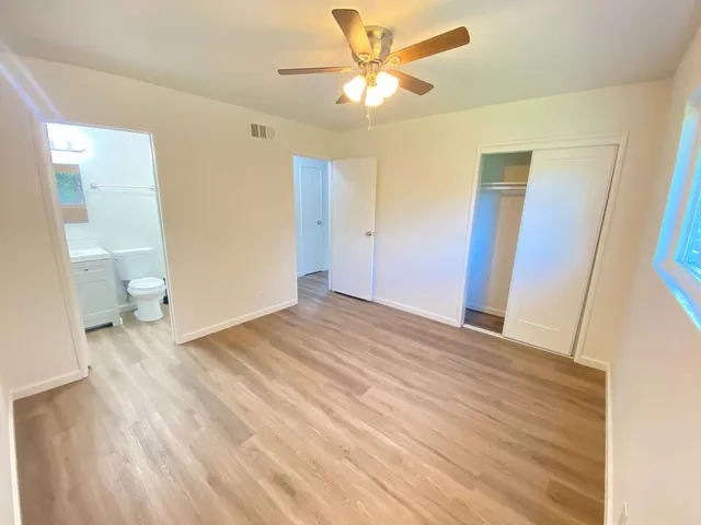 a view of a room with wooden floor and a ceiling fan