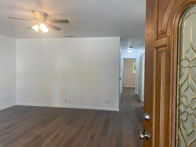 an empty room with wooden floor and a chandelier fan