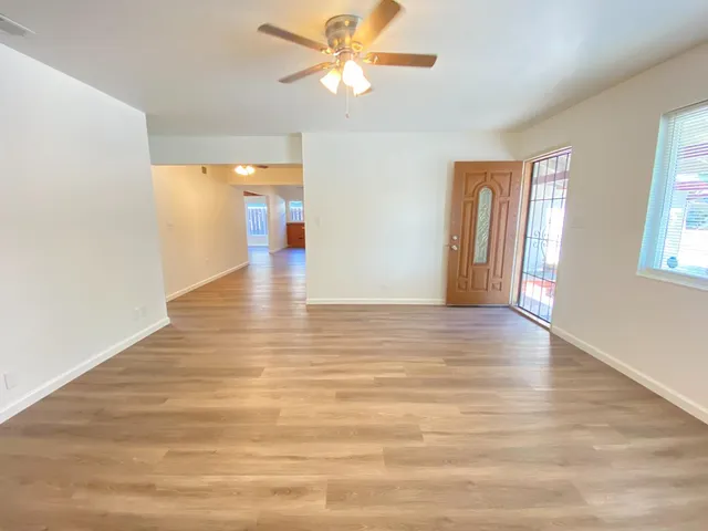a view of a room with wooden floor and a ceiling fan