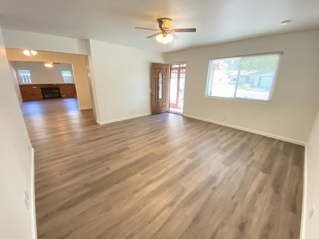 a view of empty room with wooden floor and fan