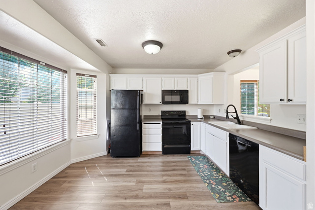 984 Independence Avenue Provo, UT 84604 - Photo 7 of 19 Kitchen featuring white cabinetry, dark countertops, black appliances, and wood-finish flooring