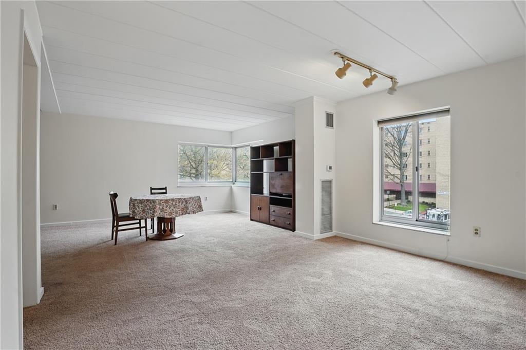 5 Bayard Road, Unit 400 Pittsburgh, PA 15213 - Photo 12 of 33 Overall, this large living room, with its warm beige carpets, is a blank canvas ready for the new occupant to infuse their personality and style, making it a true reflection of home.