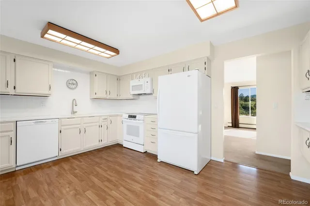 a kitchen with white cabinets white appliances and wooden floors