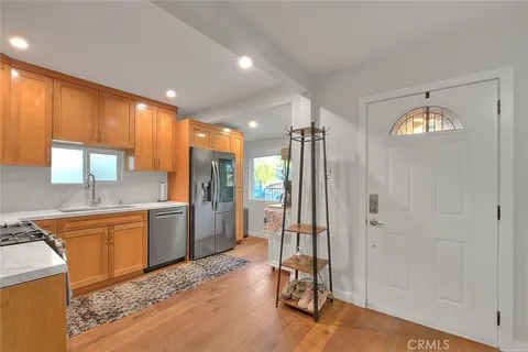 a large kitchen with a refrigerator and wooden floor