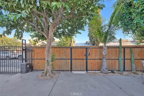 a backyard of a house with large trees and wooden fence