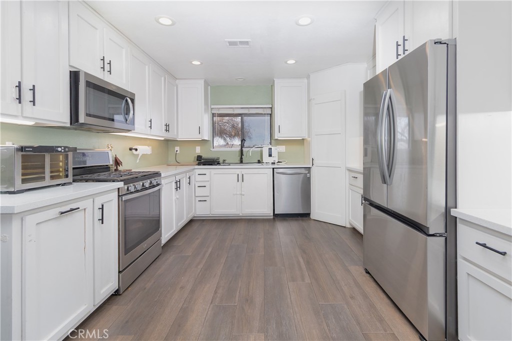 19801 Talihina Road Apple Valley, CA 92307 - Photo 7 of 32 a kitchen with a refrigerator a sink and cabinets
