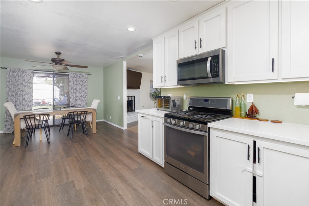 19801 Talihina Road Apple Valley, CA 92307 - Photo 10 of 32 a kitchen with granite countertop a stove a microwave a dining table and chairs with wooden floor