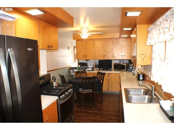 a kitchen with stainless steel appliances kitchen island granite countertop a refrigerator a sink a dining table and chairs