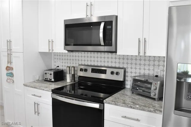 a kitchen with granite countertop stove top oven microwave and cabinets