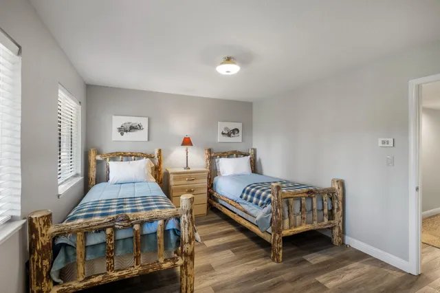 a bedroom with two beds and wooden floor