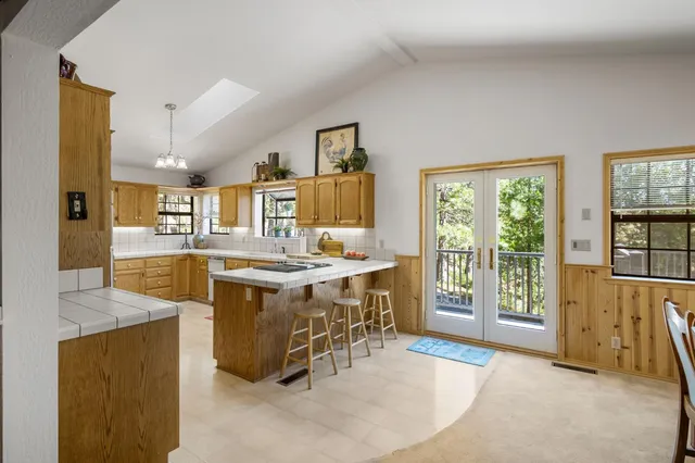 a large kitchen with kitchen island granite countertop a large window and white cabinets