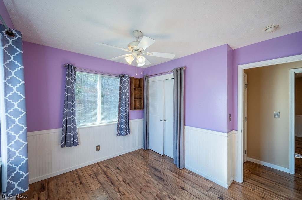 3601 River Road Vienna, WV 26105 - Photo 23 of 40 Unfurnished bedroom featuring a wainscoted wall, hardwood / wood-style floors, a closet, and a ceiling fan