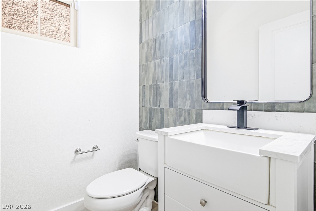 2182 Trivero Street Henderson, NV 89044 - Photo 10 of 50 Modern stone counters and a vertical tile accent wall highlight this contemporary powder room.