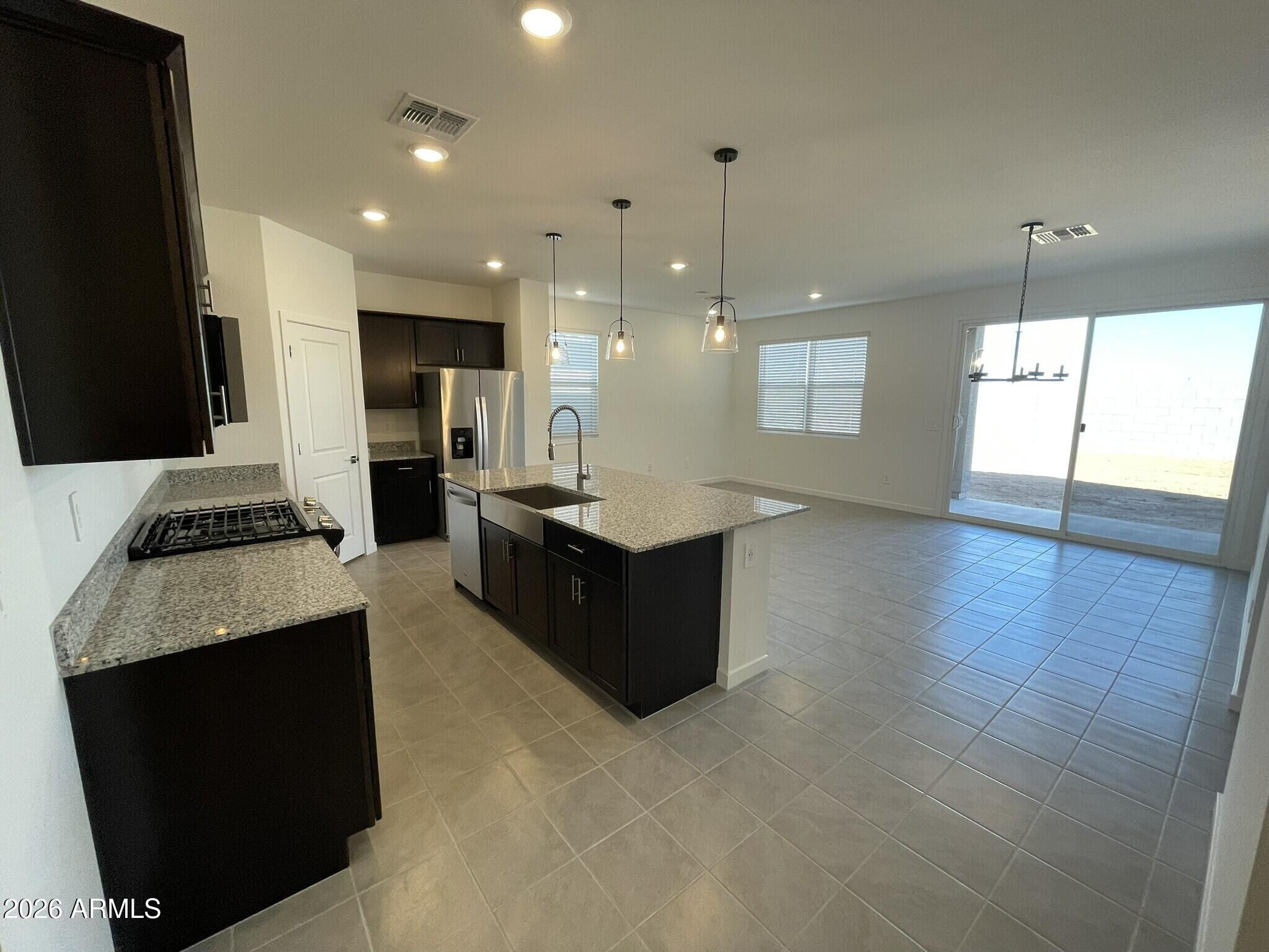 37014 West Prado Street Maricopa, AZ 85138 - Photo 10 of 18 a large living room with stainless steel appliances granite countertop a stove a sink a refrigerator and a fireplace