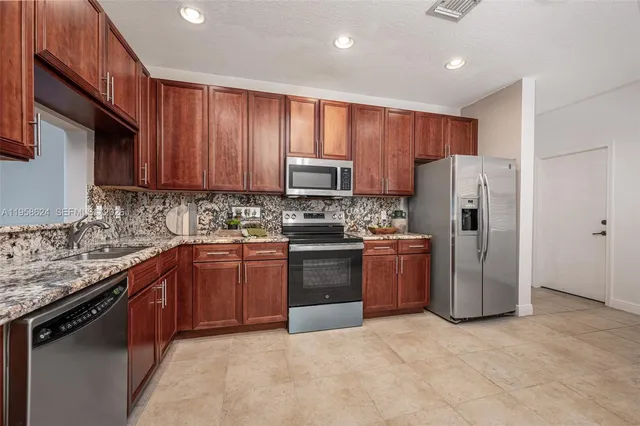 a kitchen with stainless steel appliances granite countertop a refrigerator stove and sink