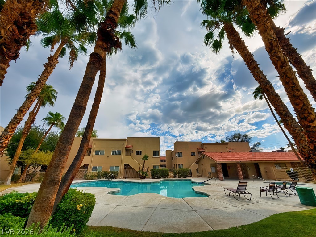 1852 North Decatur Boulevard, Unit 101 Las Vegas, NV 89108 - Photo 19 of 45 A sparkling community pool sits framed by towering palm trees under a dramatic sky.
