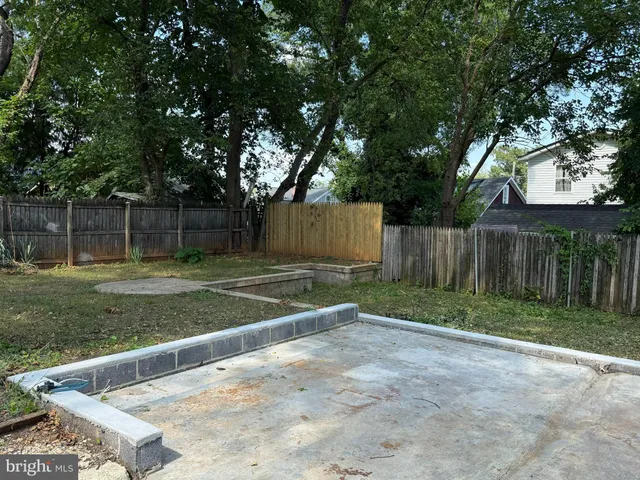 a view of a backyard with large trees and wooden fence