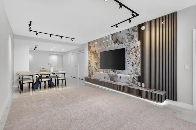 a living room with a flat screen tv a rug and white walls