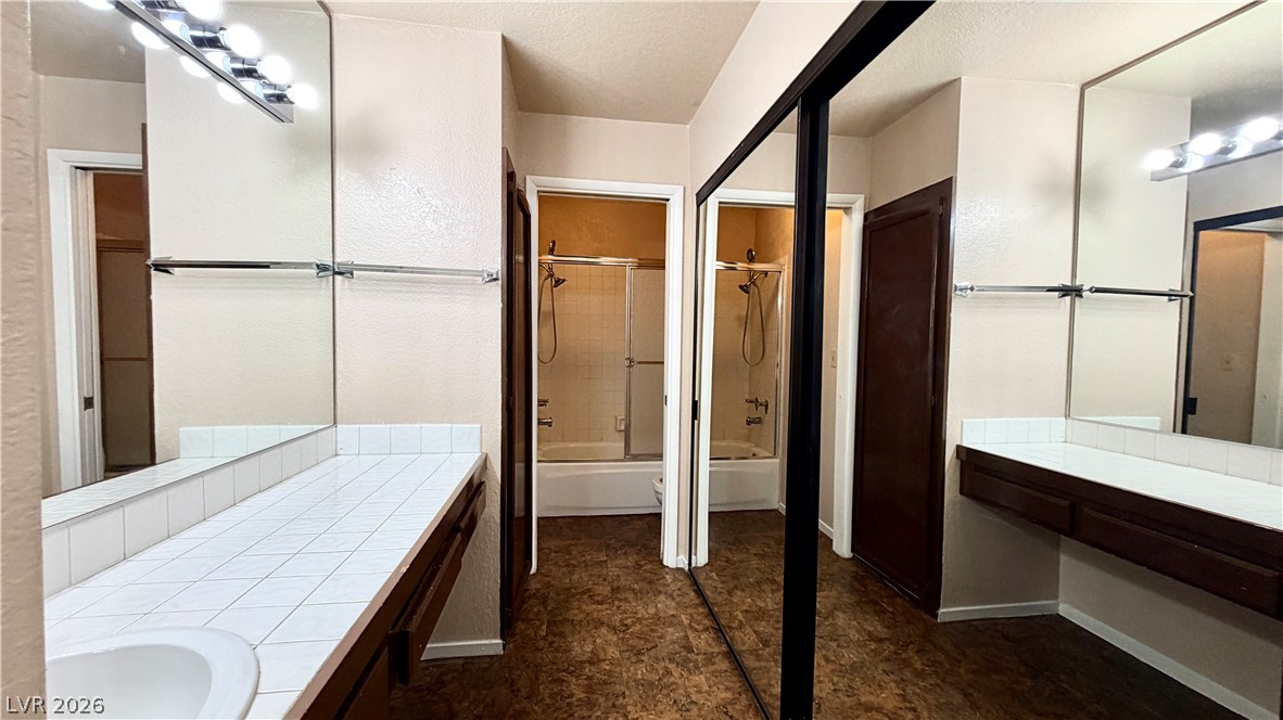 6250 West Flamingo Road, Unit 4 Las Vegas, NV 89103 - Photo 19 of 45 This bathroom features tile counters and a shower with a sliding glass door.
