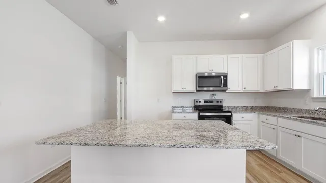 a kitchen with granite countertop white cabinets and a sink