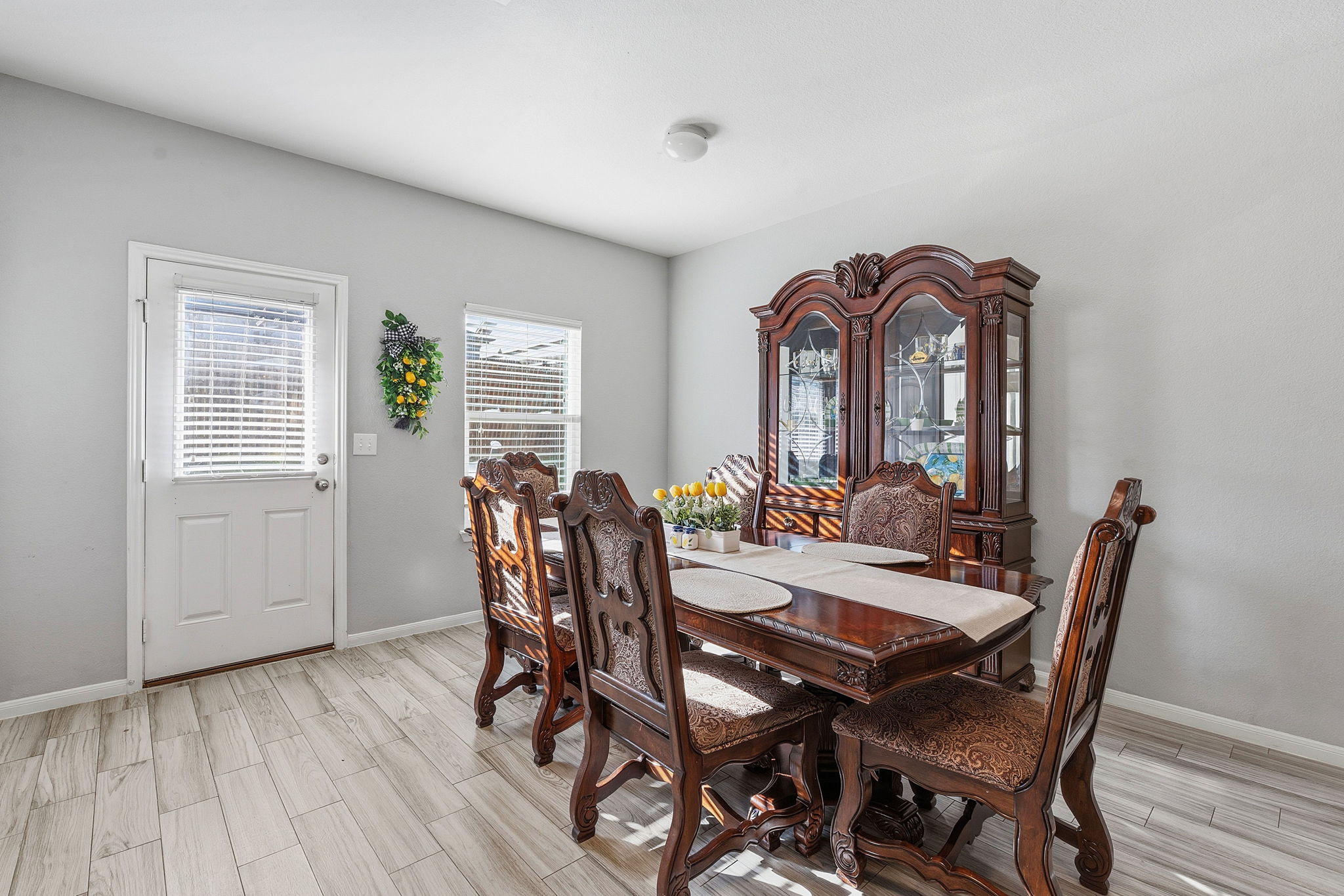 15101 Shell Bark Cove Austin, TX 78724 - Photo 10 of 26 Dining area featuring light wood-finish flooring, neutral wall tones, a white door with an integrated window blind, and a window with blinds