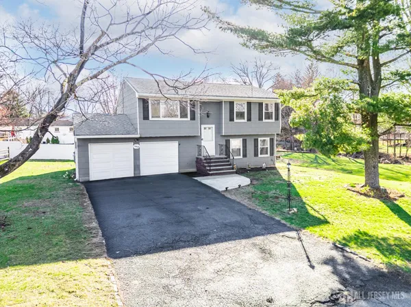 a view of a white house with a yard and a large tree