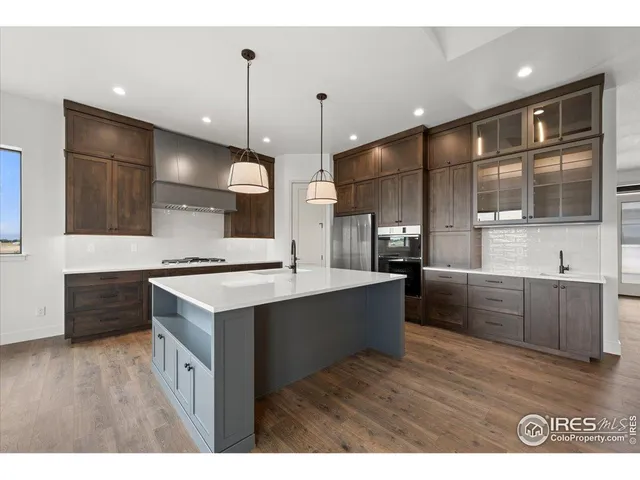 a large kitchen with a large counter top a sink stainless steel appliances and cabinets