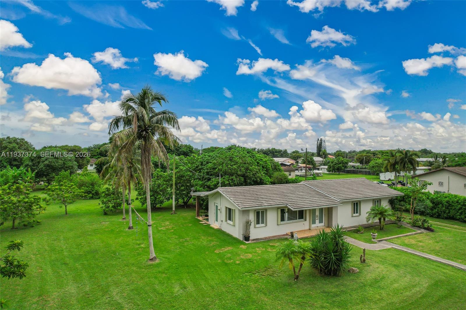 20890 Southwest 236th Street Homestead, FL 33031 - Photo 6 of 47 a view of a white house with a big yard plants and large trees