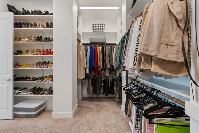 a view of walk in closet with clothes and shoes