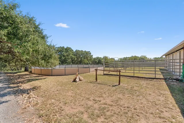 a view of a backyard with lawn chairs wooden fence and large trees